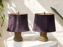 Load image into Gallery viewer, Pair of vintage table lamps with ornate aged metal bases, deep plum velvet shades, patterned shade interiors, and decorative finials