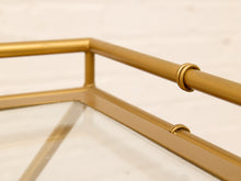 Load image into Gallery viewer, Close-up of a gold metal frame with a clear glass surface, showing the corner joint and a small ring detail on the armrest.