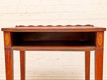 Load image into Gallery viewer, A vintage wooden side table with a warm reddish-brown finish, featuring decorative sunburst inlays on the front corners and a scalloped apron, set against a white painted brick wall.