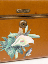 Load image into Gallery viewer, Close-up of a vintage orange-brown wooden box with a brass lock and a painted floral design featuring green leaves, a white calla lily, and a small bird. The brand name 'Campanile' is embossed on a brass plate near the top.