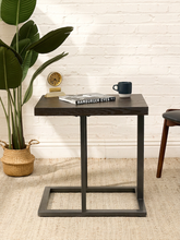 Load image into Gallery viewer, A dark wood and metal side table styled in a room setting with a white brick wall, a potted plant, a small clock, a magazine, and a mug on top.