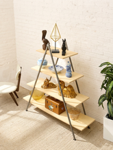 Load image into Gallery viewer, A modern A-frame wooden shelf with five tiers, styled with various decorative objects including ceramic vases, a small wooden chest, and sculptures, set against a white brick wall and beige carpet.
