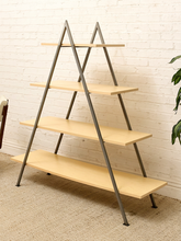 Load image into Gallery viewer, A four-tier A-frame ladder shelf with light natural wood shelves and a dark gray metal frame, set against a white brick wall and beige carpet.