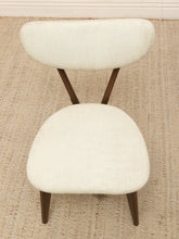 Load image into Gallery viewer, A mid-century modern accent chair with a cream-colored textured fabric upholstery and dark brown wooden legs, positioned on a woven jute rug.