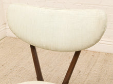 Load image into Gallery viewer, Close-up of a mid-century modern chair featuring a curved, cream-colored upholstered backrest with a visible woven texture and dark brown wooden legs.