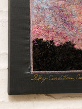 Load image into Gallery viewer, Close-up of a textured canvas art piece showing a colorful pink and blue sky above a black landscape silhouette, mounted on a dark gray canvas with gold script text at the bottom.