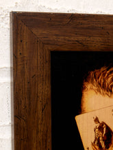 Load image into Gallery viewer, Close-up of a dark brown wooden picture frame showing the corner and a portion of a printed artwork with a black background and warm-toned illustration.