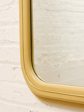 Load image into Gallery viewer, A close-up of a yellow-painted wooden mirror frame with a rounded corner, mounted against a white brick wall.