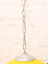 Load image into Gallery viewer, A close-up of a yellow pendant light with a silver metal chain and base, set against a white brick wall background.