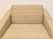 Load image into Gallery viewer, A close-up of a striped upholstered armchair with a backrest and seat cushion, shown against a white painted brick wall.