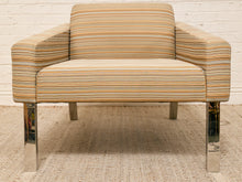 Load image into Gallery viewer, A mid-century modern armchair with a beige, brown, and orange striped fabric upholstery and polished chrome legs, set against a white brick wall and textured rug.