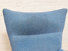 Load image into Gallery viewer, A close-up of a blue textured fabric headboard or upholstered chair backrest against a white painted brick wall.