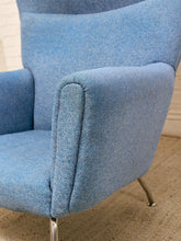 Load image into Gallery viewer, A close-up of a mid-century modern wingback armchair upholstered in textured light blue fabric, showing the armrest, backrest, and a portion of the chrome metal legs.
