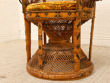 Load image into Gallery viewer, A close-up of a vintage wicker chair featuring a tiered basketweave design, a yellow patterned cushion, and dark woven accents, set against a white brick wall and beige carpet.