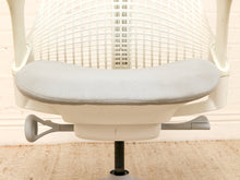 Load image into Gallery viewer, Close-up of a modern ergonomic office chair with a light gray upholstered seat cushion and a cream-colored mesh backrest, set against a light wood background.