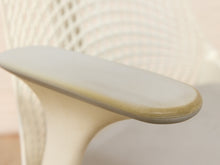Load image into Gallery viewer, Close-up detail of a modern office chair armrest with a smooth curved top and a cream-colored mesh backrest.