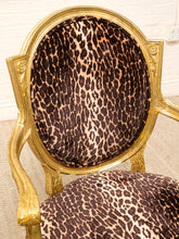 Load image into Gallery viewer, A close-up of an ornate armchair with a gold gilded frame and leopard-print upholstery in brown, black, and beige.