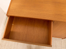 Load image into Gallery viewer, Close-up of a mid-century modern wooden desk with a drawer pulled open, showing the warm medium-brown wood grain finish and interior.