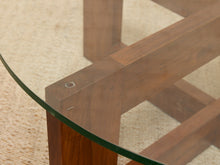 Load image into Gallery viewer, Close-up of a wooden table base with a glass tabletop, showing the corner joint and wood grain on a beige textured rug.