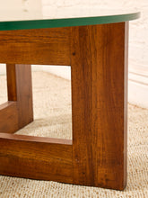 Load image into Gallery viewer, Close-up of a wooden table base with a green glass tabletop, showing the rich brown wood grain and a small portion of the green glass surface against a light neutral background.