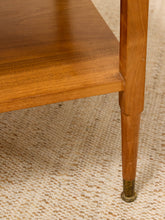 Load image into Gallery viewer, Close-up of a mid-century modern wooden table leg with a brass foot cap, resting on a textured beige woven rug.