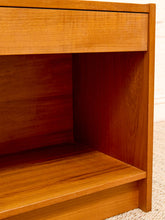 Load image into Gallery viewer, Close-up of a warm medium-brown wooden furniture piece, showing a drawer front, open shelf, and wood grain texture.