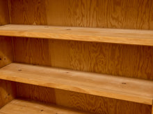 Load image into Gallery viewer, Close-up of a wooden shelving unit with three empty light brown shelves and a plywood backing.