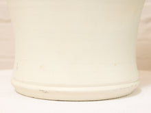 Load image into Gallery viewer, Close-up of the base and lower portion of a matte off-white ceramic vase or planter, showing a slightly tapered footed rim and subtle horizontal line details.