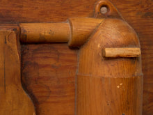 Load image into Gallery viewer, Close-up of a carved wooden object with a warm medium-brown finish, showing wood grain and a small metal screw detail against a matching wooden background.
