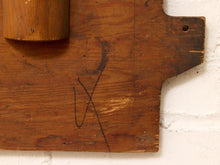 Load image into Gallery viewer, A close-up of a rustic wooden board with a dark painted black 'X' mark on it, set against a white brick wall background.