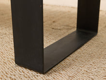 Load image into Gallery viewer, Close-up of a black metal table leg with a square cross-section, resting on a beige woven jute rug.