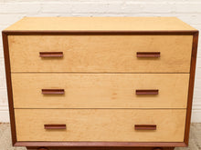 Load image into Gallery viewer, A mid-century modern three-drawer dresser with a light natural wood burl wood veneer front and a dark reddish-brown wood frame, featuring simple rectangular dark wood drawer pulls, set against a white brick wall background.