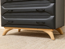 Load image into Gallery viewer, Close-up of a dark charcoal gray chest of drawers with curved drawer fronts and light natural wood legs, shown on a beige carpet.