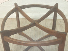 Load image into Gallery viewer, A close-up of a dark brown wooden chair frame or stool base with curved legs and crossed support bars, set against a light woven rug and white brick wall.