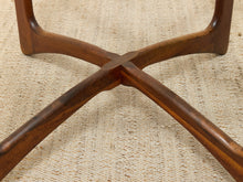 Load image into Gallery viewer, Close-up of a dark brown wooden table base with curved legs and a central cross joint, resting on a beige woven rug.
