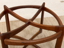 Load image into Gallery viewer, Close-up of a mid-century modern wooden stool base with curved armrests and a geometric star-like frame design, made of rich dark brown wood on a beige rug against a white brick wall.