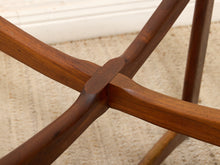Load image into Gallery viewer, Close-up of a wooden table base with four intersecting legs and a central joint, shown on a beige carpeted floor.