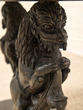 Load image into Gallery viewer, Close-up of a dark carved wooden lion figurine holding a horse's head, with detailed wood grain and shadows against a light beige background.