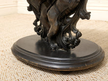 Load image into Gallery viewer, Close-up of a dark bronze sculpture of horse legs and draped fabric mounted on a round black pedestal base, set on a beige woven rug.