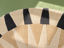 Load image into Gallery viewer, A close-up of a textured rug featuring a geometric fan-like pattern with alternating beige, tan, and black wedge shapes.