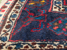 Load image into Gallery viewer, Close-up of a traditional patterned rug showing a deep navy blue field with red and turquoise motifs, bordered by cream, brown, and blue patterns.