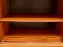 Load image into Gallery viewer, Close-up of the interior of a wooden cabinet or shelf unit with two empty shelves, showing warm medium-brown wood grain and dark backing panels.
