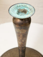 Load image into Gallery viewer, An antique bronze candlestick with a conical stem and a wide flared top showing a greenish patina, set against a neutral light background.