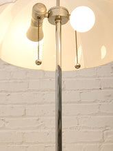 Load image into Gallery viewer, A close-up of a vintage-style floor lamp with a large white dome shade, a polished silver metal pole, and two pull-chain switches, set against a white painted brick wall.