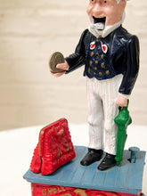 Load image into Gallery viewer, A vintage collectible toy bank or figurine featuring a performer standing on a blue platform with a red suitcase and green umbrella, photographed against a light neutral background.