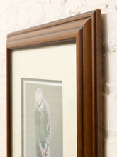 Load image into Gallery viewer, A close-up of a dark brown wooden picture frame with a cream mat and a framed print leaning against a textured white brick wall.