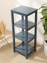 Load image into Gallery viewer, A three-tier wooden side table in a muted slate blue-gray finish, styled in a room setting with a white brick wall, beige rug, a chair on the left, and a green plant on the right.