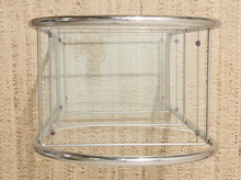 Load image into Gallery viewer, A clear acrylic or glass cylindrical side table with a polished silver metal frame, set against a textured beige woven fabric background.