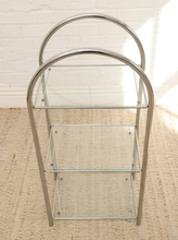 Load image into Gallery viewer, Vintage three-tier display shelf with polished chrome tubular frame, clear glass shelves, and tall rounded supports