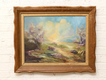 Load image into Gallery viewer, Vintage pastoral landscape painting with flowering trees, winding country path, distant hills, and soft blue and green tones in a warm wood frame.